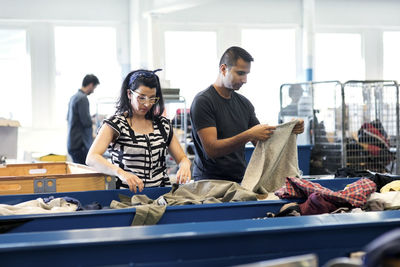 Volunteers checking clothes on conveyor belt at workshop