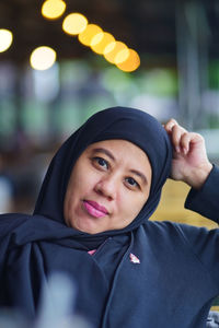 Portrait of indonesian muslim woman wearing black hijab with bokeh.