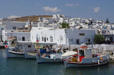 Boats in sea by town against sky