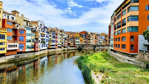 Buildings by canal against sky in city