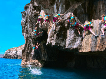 People standing on rock against waterfall