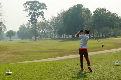 Rear view of man standing on golf course