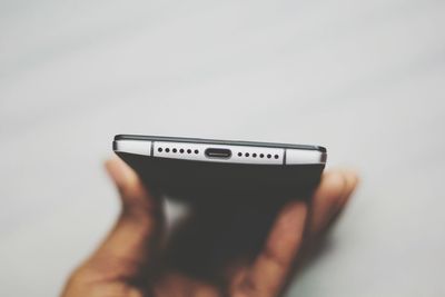 Close-up of hand holding smart phone over white background