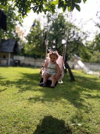 Cute baby girl sitting on swing at park