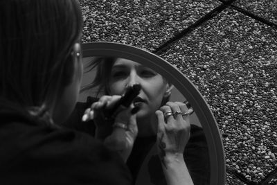 Beautiful woman applying make up looking at mirror