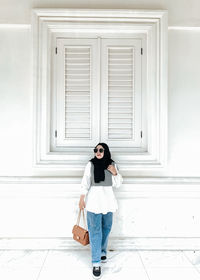 Rear view of woman standing against wall