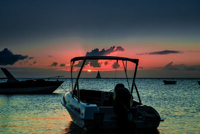 Silhouette boat in sea against sky during sunset