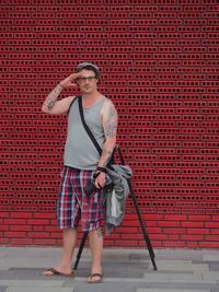 Full length of man standing against red wall