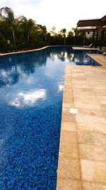 Swimming pool by trees against sky