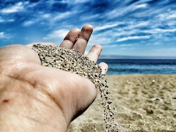 Close-up of hand holding sand at beach