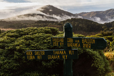 Information sign against trees and mountains against sky