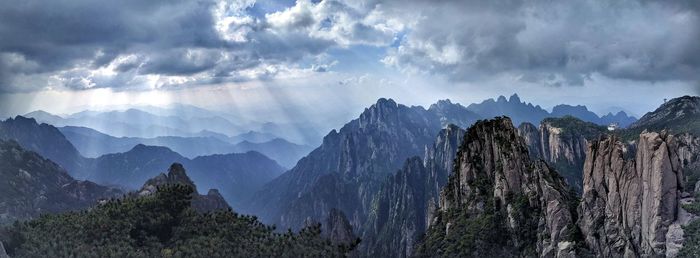 Panoramic view of rocky mountains against cloudy sky