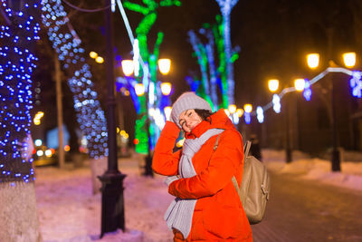 Woman standing in illuminated city during winter