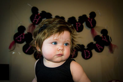 Cute baby girl looking away while sitting at home during birthday party