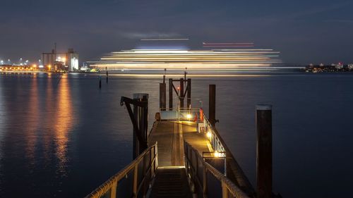 Illuminated pier on sea at night