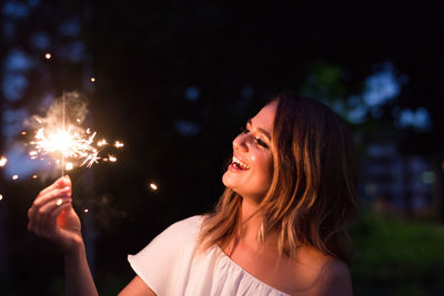 Smiling woman with sparklers at night