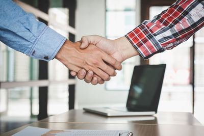 Midsection of businessmen shaking hands in office