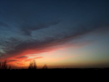 Silhouette landscape against dramatic sky during sunset