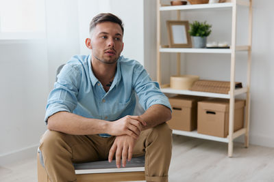 Portrait of young man sitting on sofa at home