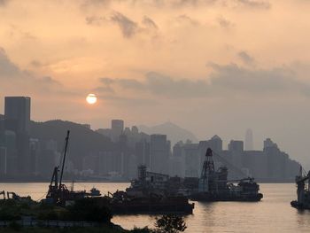 Scenic view of sea by buildings against sky during sunset