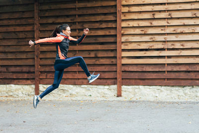 Full length of young woman exercising on field