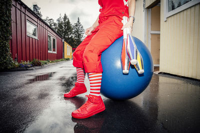 Low section of woman with juggling pins sitting on fitness ball