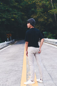Rear view of young man standing on footpath