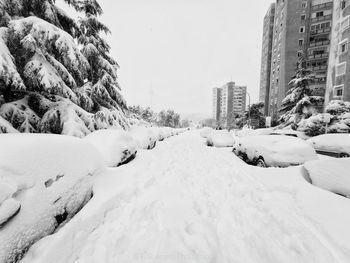 Snow covered buildings in city against clear sky