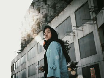 Low angle view of woman standing against building in city