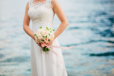 Midsection of woman holding flower against blurred background