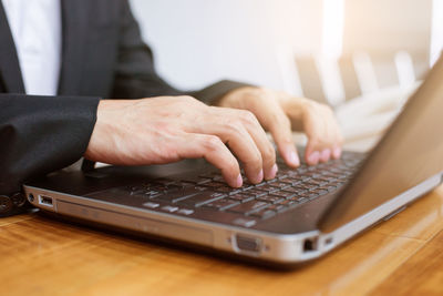 Midsection of man using laptop on table