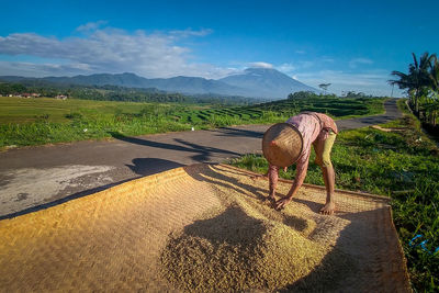 Man drying grains while standing on wicker basket