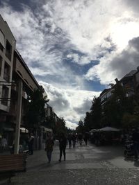 People walking on street in city against sky