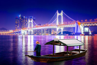 Illuminated bridge over river against sky at night
