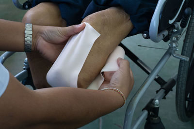 Cropped hand of doctor wrapping bandage on prosthesis leg in hospital