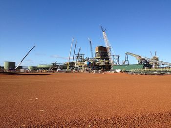 Cranes at commercial dock against clear blue sky