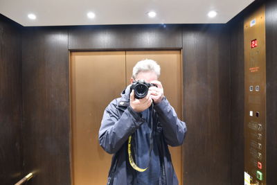 Full length of man photographing in illuminated camera