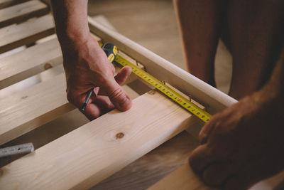 Midsection of man measuring wood at home