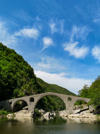 Arch bridge over river against sky