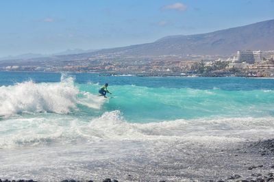 Man surfing in sea against sky