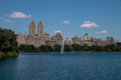 View of buildings by river against cloudy sky