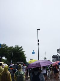 Crowd on street in city against clear sky