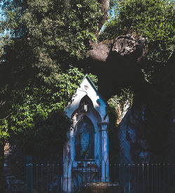 Low angle view of cross amidst trees and building