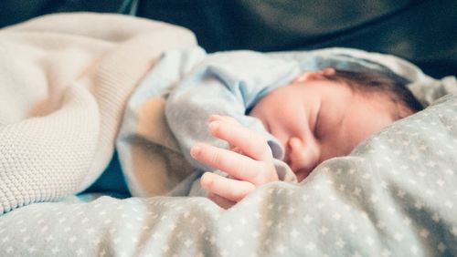 Close-up of newborn baby sleeping on bed at home