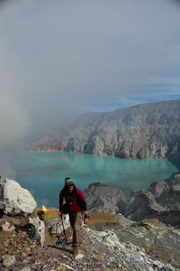 Rear view of man looking at waterfall against sky