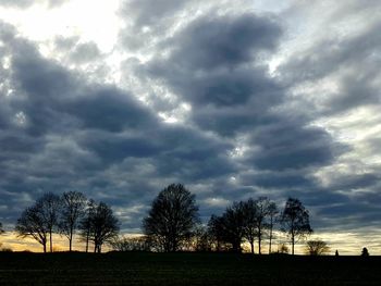 Silhouette trees on field against sky