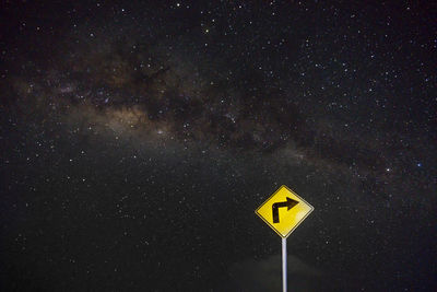 Road sign against sky at night