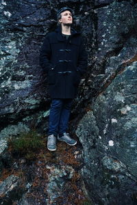 Young man standing against rock