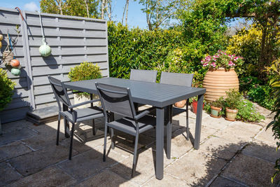 Empty chairs and table by potted plants in yard