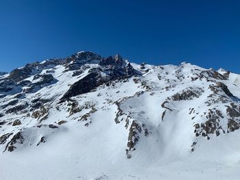 Scenic view of snow covered mountains against clear blue sky